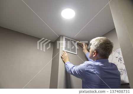 A person installing or maintaining an HVAC return air vent grille A person installing or maintaining an HVAC return air vent grille 137408731