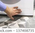 Man opening the drain pump filter access panel of the front loading washing machine 137408735