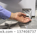 Man opening the drain pump filter access panel of the front loading washing machine 137408737