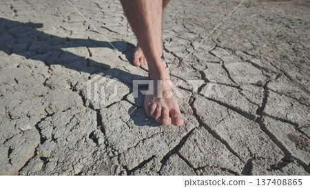A man walks barefoot through mud and swampy cracked earth. A man walks barefoot through mud and swampy cracked earth. 137408865