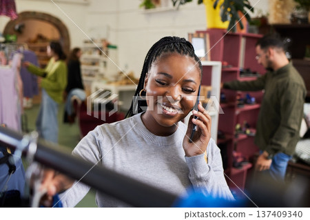 Shopping, woman and phone call for talking fashion at a retail store with sale or discount. Black person or happy customer on smartphone for product choice, promotion or communication in a boutique Shopping, woman and phone call for talking fashion at a retail store with sale or discount. Black person or happy customer on smartphone for product choice, promotion or communication in a boutique 137409340