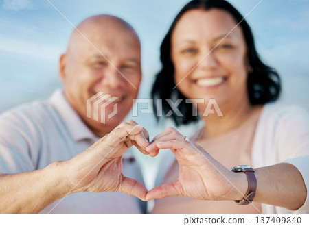 Heart shape, hands and mature couple at the beach on a romantic vacation, adventure or holiday. Smile, emoji and portrait of man and woman in retirement with love or support gesture by ocean on trip. 137409840