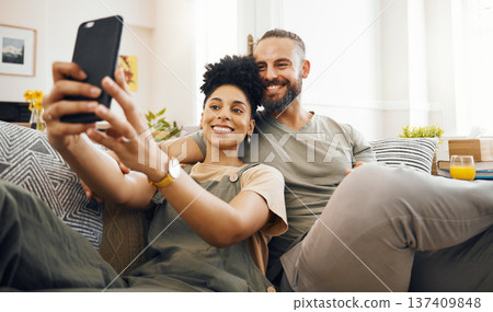 Interracial couple, selfie and happy on couch, relax at home with social media, streaming and memory with commitment. Smile in picture, post and love, care and trust, people in lounge with romance 137409848