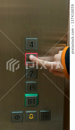 The child is pressing the button in the elevator. The child is pressing the button in the elevator. 137410059