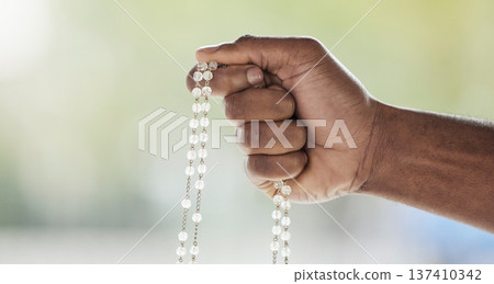 Rosary, person hand and prayer beads in a home with hop, christian praise and religion. Praying, necklace and worship in a house with hope, gratitude and spiritual guide for support and healing Rosary, person hand and prayer beads in a home with hop, christian praise and religion. Praying, necklace and worship in a house with hope, gratitude and spiritual guide for support and healing 137410342