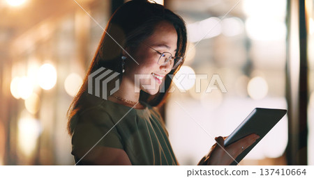 Asian woman, tablet and typing in night office while working on project deadline. Digital tech, touchscreen and happy business woman working late in dark workplace, researching and writing email. Asian woman, tablet and typing in night office while working on project deadline. Digital tech, touchscreen and happy business woman working late in dark workplace, researching and writing email. 137410664