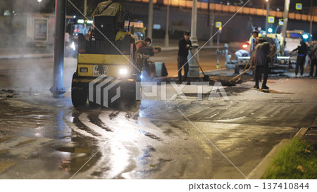 Road roller compacting hot asphalt on city street at night, workers repairing Road roller compacting hot asphalt on city street at night, workers repairing 137410844