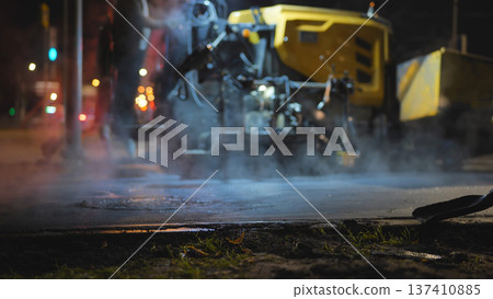 Asphalt paver machine working late at night, repairing city road surface 137410885