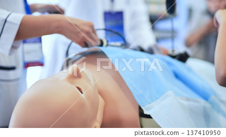 Medical students practicing laparoscopic surgery on a realistic training mannequin Medical students practicing laparoscopic surgery on a realistic training mannequin 137410950