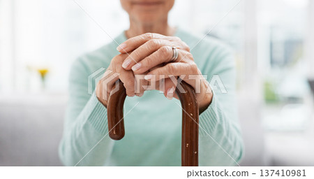 Hands, walking stick and elderly woman with walking stick on a sofa for balance, support and mobility. Walk, aid and old female at senior care facility with disability, dementia or chronic arthritis 137410981