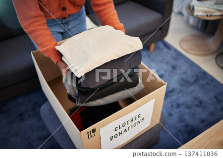 Donation box, charity and hands with clothes for nonprofit and cardboard container at home. Moving, donating and house with giveaway and spring cleaning for community care support with packing 137411036