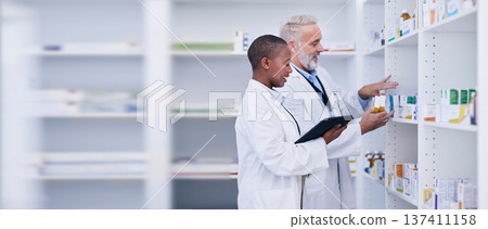 Discussion, tablet and pharmacists checking medication for inventory, stock or medical research. Healthcare, medicine and senior chemist mentor teaching female pharmaceutical student with technology. Discussion, tablet and pharmacists checking medication for inventory, stock or medical research. Healthcare, medicine and senior chemist mentor teaching female pharmaceutical student with technology. 137411158