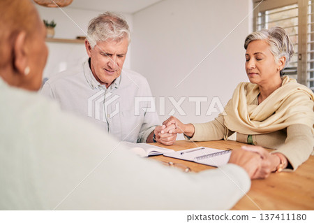 Elderly friends, prayer and holding hands in home, bible study and hope in spiritual faith. Senior people, group and religion at table together, support and worship Holy Spirit, Jesus Christ and God 137411180