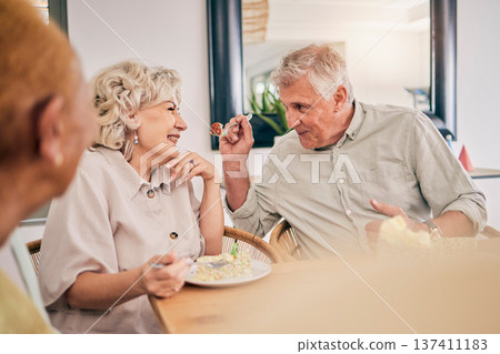 Food, retirement and a senior couple in an assisted living home while eating a meal for nutrition. Cute, love or smile with a happy elderly man feeding his wife in the dining room of a house 137411183