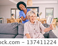 Nurse brush hair of senior woman in the living room of the modern retirement home for self care. Mirror, routine and African female caregiver doing a hairstyle for an elderly patient in the lounge. 137411224