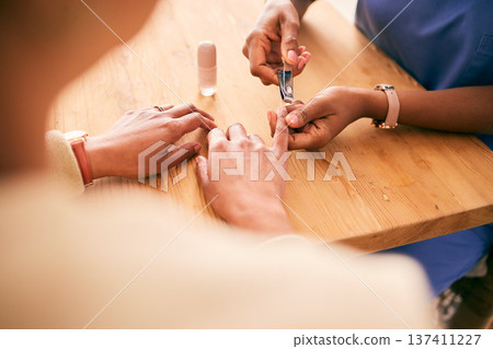 Cosmetics, grooming and hands for home manicure, beauty treatment or service at a table. Spa, wellness and closeup of person with a client for the process of cutting nails for luxury care on fingers Cosmetics, grooming and hands for home manicure, beauty treatment or service at a table. Spa, wellness and closeup of person with a client for the process of cutting nails for luxury care on fingers 137411227