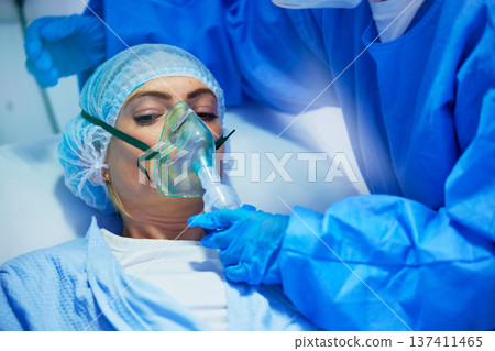 Surgery, anesthesia and doctor with woman with oxygen mask for medical service, operation and procedure. Healthcare, hospital and surgeons with gas, breathing and ventilation equipment for patient 137411465