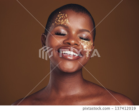 Gold, glitter and black woman smile from beauty with makeup and studio with sparkle cosmetics. Brown background, relax and female model with golden paint for skin glow and creative facial shine Gold, glitter and black woman smile from beauty with makeup and studio with sparkle cosmetics. Brown background, relax and female model with golden paint for skin glow and creative facial shine 137412019