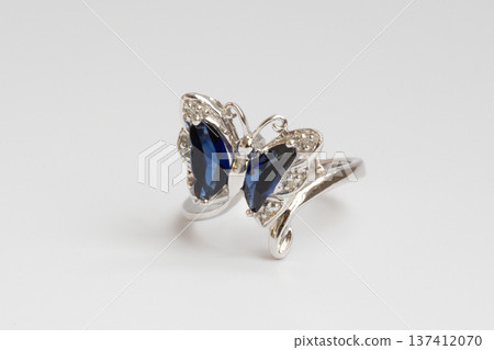 A women's piece of jewelry made of white gold, diamonds, and sapphires in the shape of a butterfly on a white background. A women's piece of jewelry made of white gold, diamonds, and sapphires in the shape of a butterfly on a white background. 137412070
