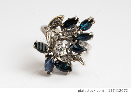 The ring features a white gold setting with a round diamond and marquise-cut sapphires on a white background. The ring features a white gold setting with a round diamond and marquise-cut sapphires on a white background. 137412072