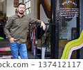 Man, portrait or fashion shop door of clothes, thrift store or workshop entrance to sale, cool or charity clothing. Confident professional, designer or small business owner in retail donation startup 137412117
