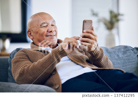 Smile, typing and a senior man with a phone on the sofa for social media, contact or commmunication. Happy, relax and an elderly person on the home couch with a mobile for an app or reading a chat Smile, typing and a senior man with a phone on the sofa for social media, contact or commmunication. Happy, relax and an elderly person on the home couch with a mobile for an app or reading a chat 137412295