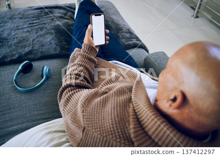Phone screen, mockup and a man on a home sofa for internet advertising with social media or a website. Behind a person with a smartphone and blank space for network, streaming music and headphones Phone screen, mockup and a man on a home sofa for internet advertising with social media or a website. Behind a person with a smartphone and blank space for network, streaming music and headphones 137412297