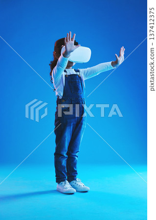 Metaverse, girl and kid virtual reality glasses, futuristic or online gaming on a blue studio background. Child, vr headset or model with video game, technology or augmented reality with mockup space Metaverse, girl and kid virtual reality glasses, futuristic or online gaming on a blue studio background. Child, vr headset or model with video game, technology or augmented reality with mockup space 137412375