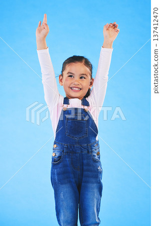 Success, girl child and champion, winner and achievement with happiness and excited isolated on blue background. Cheers, yes and winning with celebration, pride and happy kid with arms up in a studio Success, girl child and champion, winner and achievement with happiness and excited isolated on blue background. Cheers, yes and winning with celebration, pride and happy kid with arms up in a studio 137412470