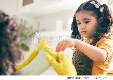 Girl, mom and kitchen to put rubber gloves on hands, helping and show skills in family home. Spring cleaning, mother and daughter by ppe, hygiene and teaching for safety, bacteria and dirt in house Girl, mom and kitchen to put rubber gloves on hands, helping and show skills in family home. Spring cleaning, mother and daughter by ppe, hygiene and teaching for safety, bacteria and dirt in house 137412522