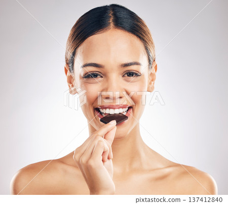 Woman, eating chocolate and portrait for skincare, beauty and wellness, health or diet on white background. Young person or face of model with cacao or candy for skin care and dermatology in studio Woman, eating chocolate and portrait for skincare, beauty and wellness, health or diet on white background. Young person or face of model with cacao or candy for skin care and dermatology in studio 137412840