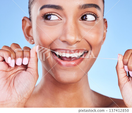 Woman, smile and floss teeth in studio for healthy dental care, gum gingivitis or plaque on blue background. Face, happy indian model and oral thread for cleaning mouth, fresh breath or tooth hygiene Woman, smile and floss teeth in studio for healthy dental care, gum gingivitis or plaque on blue background. Face, happy indian model and oral thread for cleaning mouth, fresh breath or tooth hygiene 137412850