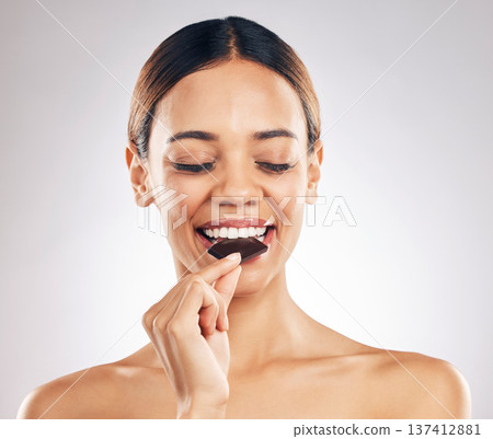 Woman, eating chocolate and thinking of diet for skincare, beauty and inner health on white background. Young person or model with cacao product, food or candy for skin care or dermatology in studio 137412881