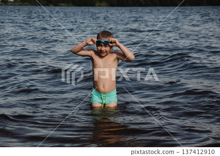 child happily excitedly enters water, swims, dives lake or pond on a hot, sunny summer day during vacation or school break. active healthy lifestyle. child wearing turquoise swimming trunks goggles. child happily excitedly enters water, swims, dives lake or pond on a hot, sunny summer day during vacation or school break. active healthy lifestyle. child wearing turquoise swimming trunks goggles. 137412910