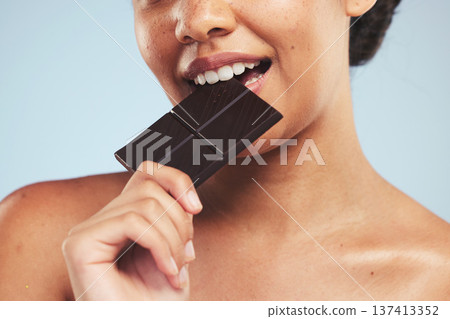 Eating, chocolate and woman in studio with unhealthy, diet or luxury snack on blue background. Sugar, bite and lady model with cocoa candy bar craving, addiction or sweet satisfaction while isolated 137413352