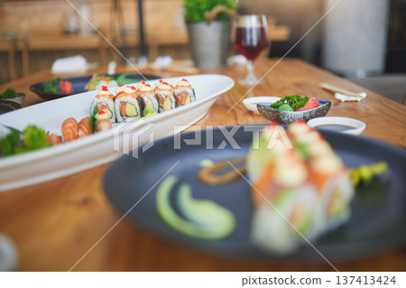 Sushi, chinese food and chopsticks in an asian restaurant closeup for fine dining or traditional cuisine. Salmon, menu and seafood with a dish on a table in a local eatery for hunger or nutrition Sushi, chinese food and chopsticks in an asian restaurant closeup for fine dining or traditional cuisine. Salmon, menu and seafood with a dish on a table in a local eatery for hunger or nutrition 137413424