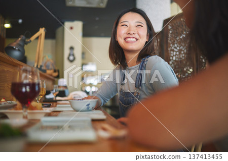 Happy, eating and friends at a restaurant for food, conversation or bonding together. Smile, excited and an Asian girl or women at a cafe for fine dining, talking and hungry at a table with people 137413455