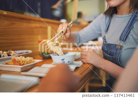 Hands, chopsticks and woman with shrimp in restaurant, fine dining and eating in cafe store. Sushi, sticks and person on prawn, tempura food and fish meat in bowl for lunch, brunch and seafood meal Hands, chopsticks and woman with shrimp in restaurant, fine dining and eating in cafe store. Sushi, sticks and person on prawn, tempura food and fish meat in bowl for lunch, brunch and seafood meal 137413461