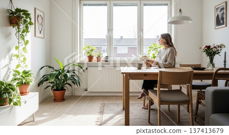 一幅展現新生活的畫面：一位女性在擺滿綠植的明亮客廳閱讀。 137413679