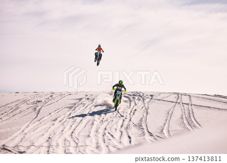 Dune, jump and men in motorbike race together for practice, training and extreme sports energy. Professional dirt biking challenge, friends and danger with off road motorcycle competition in desert. 137413811