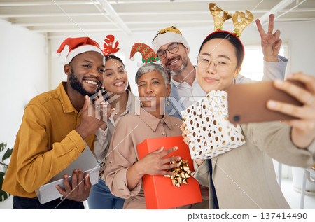 Business people, Christmas selfie and happy staff with present, peace sign or celebration for diversity at party. Men, women and photography for funny xmas memory, friends or gift for social network Business people, Christmas selfie and happy staff with present, peace sign or celebration for diversity at party. Men, women and photography for funny xmas memory, friends or gift for social network 137414490
