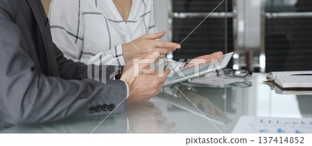 Business people collaborating with tablet, analyzing corporate data during a meeting for strategic planning. Businesspeople concept Business people collaborating with tablet, analyzing corporate data during a meeting for strategic planning. Businesspeople concept 137414852