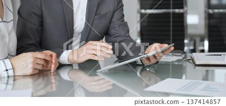 Business people hands discussing data on digital tablet during an office meeting, planning strategy and analyzing results Business people hands discussing data on digital tablet during an office meeting, planning strategy and analyzing results 137414857