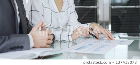 Business partners analyzing corporate data during a meeting, discussing financial reports and market trends. Business-people concept Business partners analyzing corporate data during a meeting, discussing financial reports and market trends. Business-people concept 137415078