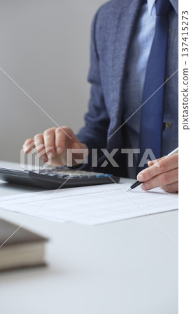 Professional accountant calculating expenses, documenting financial details on notepad while working at corporate desk. Audit and taxes in business Professional accountant calculating expenses, documenting financial details on notepad while working at corporate desk. Audit and taxes in business 137415273