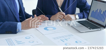 Businessman and business woman reviewing financial documents, collaborating over laptop screen, analyzing market charts for strategic corporate planning. Businesspeople and finance concept Businessman and business woman reviewing financial documents, collaborating over laptop screen, analyzing market charts for strategic corporate planning. Businesspeople and finance concept 137415283