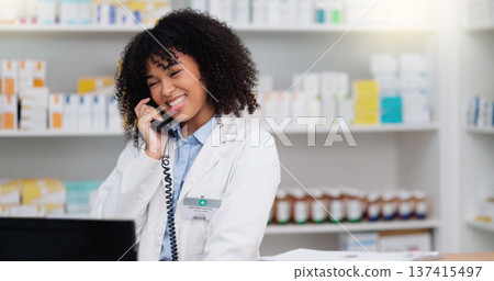 Friendly pharmacist talking on the telephone and checking something on her computer in a pharmacy. Woman using pc to access drug database for inventory check or access customers prescription online Friendly pharmacist talking on the telephone and checking something on her computer in a pharmacy. Woman using pc to access drug database for inventory check or access customers prescription online 137415497