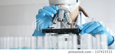 Laboratory scientist wearing blue protective gloves carefully positioning microscope slide, demonstrating research precision. Medicine, healthcare and science concept Laboratory scientist wearing blue protective gloves carefully positioning microscope slide, demonstrating research precision. Medicine, healthcare and science concept 137415515