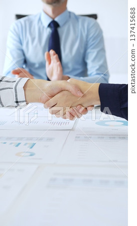 Business people shaking hands in office with financial charts, laptop and reports on table, symbolizing success, teamwork, agreement and corporate growth. Handshake concept Business people shaking hands in office with financial charts, laptop and reports on table, symbolizing success, teamwork, agreement and corporate growth. Handshake concept 137415688