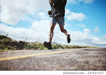 Legs, fitness and running with a man on a road on a blue sky and clouds for cardio training in a race. Exercise, health and challenge with a male runner or athlete outdoor for a workout or marathon 137415727